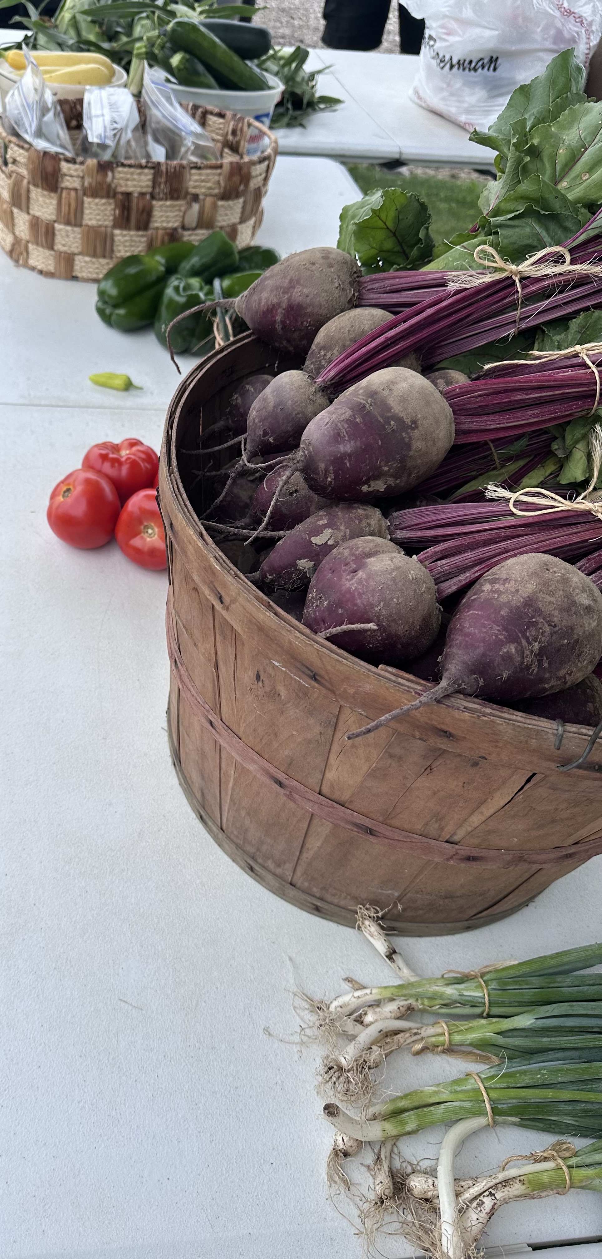 Baskets of beets, tomatoes, peppers, and green onions